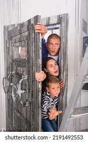 Astonished And Scared Young Man And Woman With Two Teen Boys Trying To Get Into Room Through Heavy Steel Bunker Door With Handwheels Of Locks. Reality Quest, Role Play And Family Fun Concept