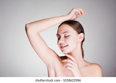 Astonished Woman Cares For The Underarm Skin On A Gray Background