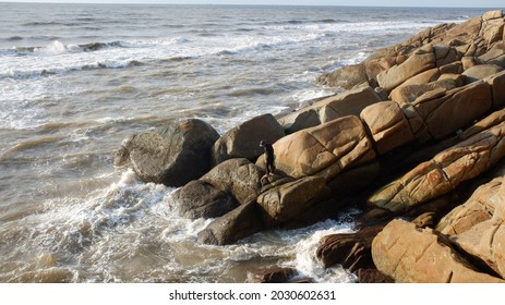 Astonishing views of ocean waves and rocky shores are astonishing with men fishing standing on a stone.