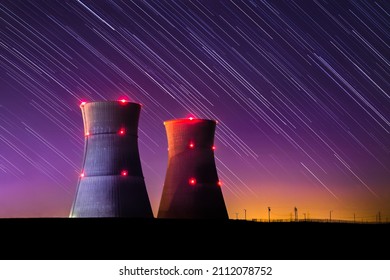 An astophotography image of nuclear power plant with colorful sunset and star trails at night