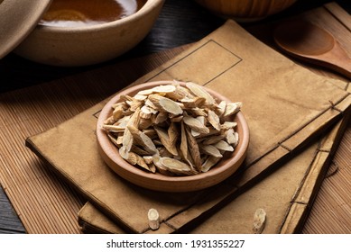 Astragalus membranaceus，Ancient Chinese medicine books and herbs on the table
