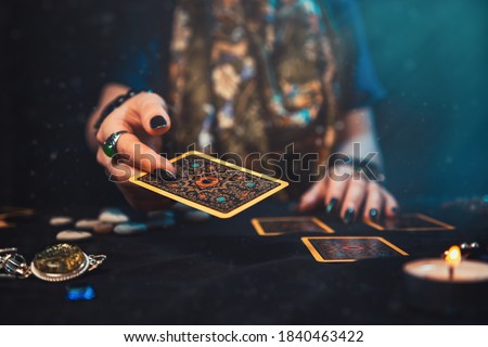Astrology and esotericism. The female hand of the sorceress throws a Tarot card. Close up