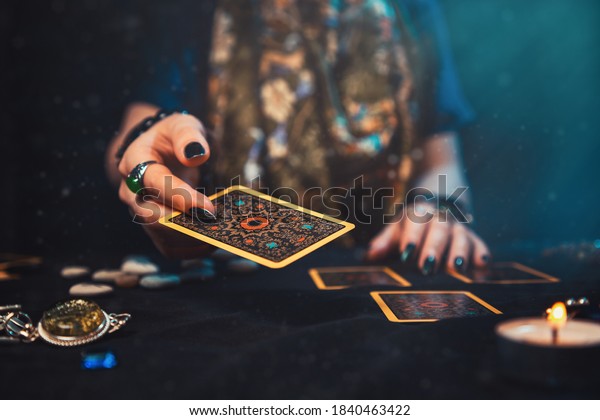 Astrology and esotericism. The female hand\
of the sorceress throws a Tarot card. Close\
up