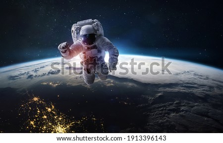 Astronaut in dark deep space. Shadow of night and lights on planet. Earth and spaceman. Sun light on background. Elements of this image furnished by NASA