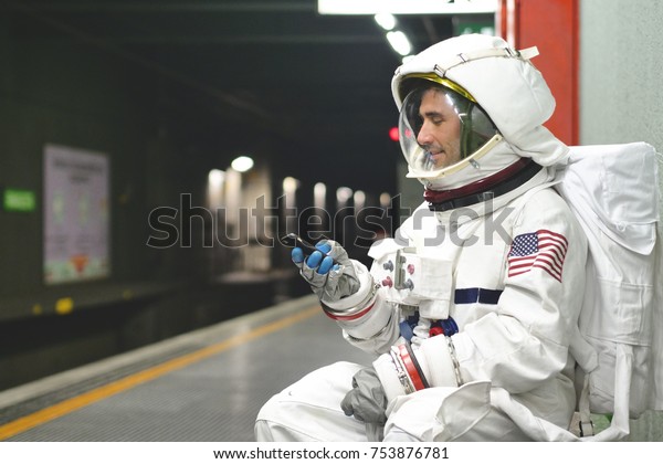 An astronaut dressed man uses the smartphone to\
call and send messages. The astronaut smiles while looking at the\
phone in his hand. Concept of: Phone Promotions, Messages and\
Spatial Calls.