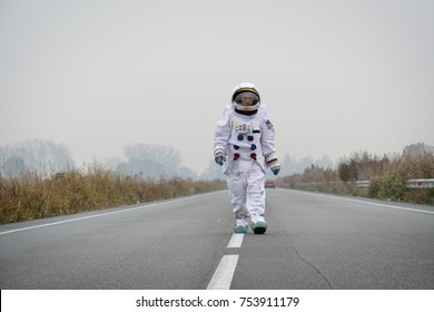 An astronaut just landed from space, on the new planet, walks in the middle of a road to explore the new world and live there. Concept of: success road, dreams, astronaut, inspiration.