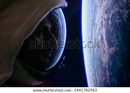 Astronaut looking deep space, galaxy and planets from the window of his capsule. Concept on science and space exploration. straight focus on the face inside the helmet!.elements furnished by NASA
