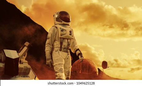 Astronaut On Mars Walking On The Exploring Expedition. In The Background His Base/ Research Station. First Manned Mission To Mars, Technological Advance Brings Space Exploration, Colonization.