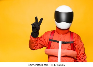 Astronaut With Orange Spacesuit Making A Victory Gesture On Yellow Background