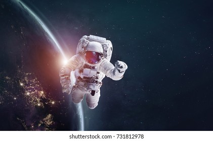 Astronaut in outer space over of the Earth with sun light. City lights on planet. Elements of this image furnished by NASA. - Powered by Shutterstock