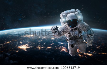 Astronaut in outer space over of the nightly Earth. City lights on background. Elements of this image furnished by NASA