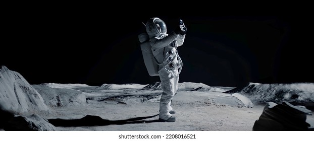 Astronauta buscando señal celular o wi-fi mientras camina sobre la superficie de la luna