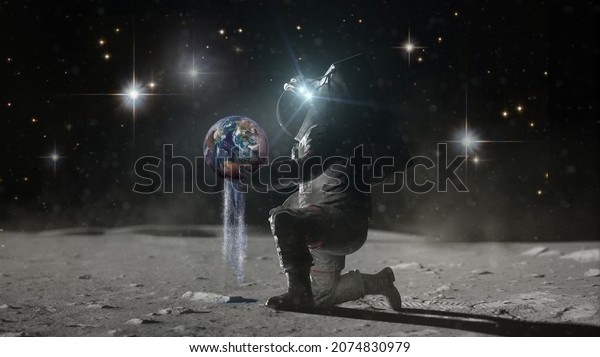 Astronaut sits on his knee on lunar surface holds\
planer Earth in hands and pours earth\'s water through his fingers.\
Water day concept. Water as a treasure. Elements of this image\
furnished by NASA.