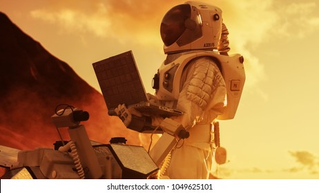 Astronaut in the Space Suit Works on Laptop, Adjusting Rover on a New Alien Red Planet, Presumably Mars. Day Light High-Tech Space Exploration, Mission, Discovering and Colonizing Habitable Planets. - Powered by Shutterstock - Get 15% off with code: PIKWIZARD15