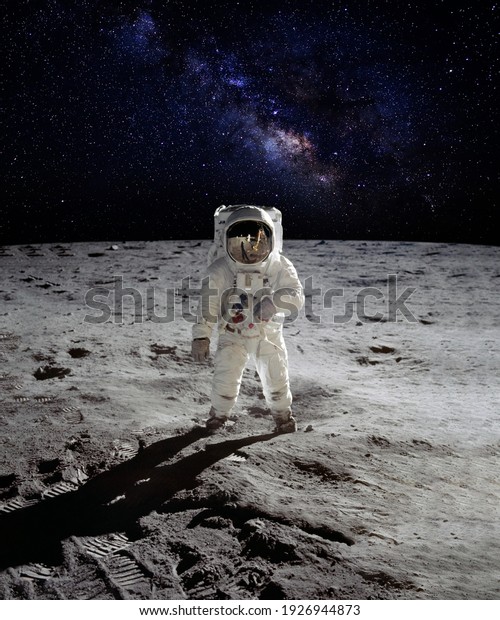An astronaut walking on the surface of the moon\
with earth on lunar landing space mission. Elements of this image\
furnished by NASA.