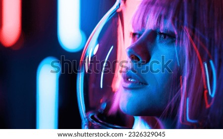 Astronaut woman with purple hair in futuristic costume over dark background. Violet neon light. Astronomy conception. Distant galaxies and deep space.