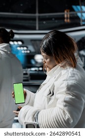 Astronauts doing tests using mockup smartphone aboard high tech starship during spaceflight. Space station crew members using green screen mobile phone to do systems analysis