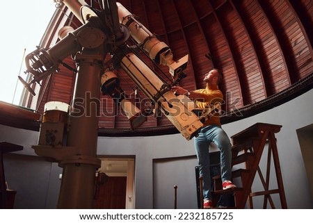 Astronomer with a big astronomical telescope in observatory doing science research.