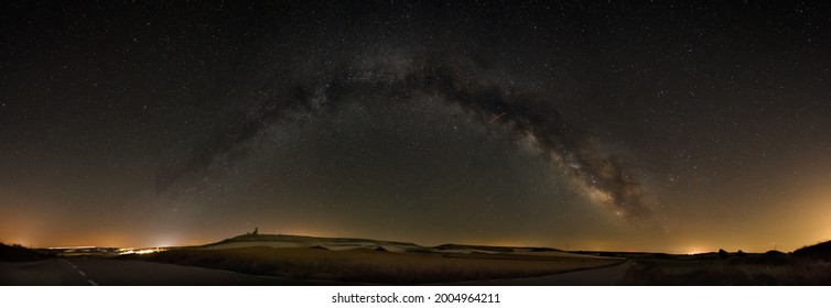 Astronomic Panorama of the arch of milky way with the ruins of old medieval castle in Sapin