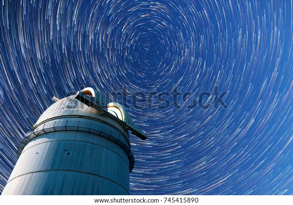 Astronomical observatory under the night sky stars. Blue sky with hundreds of stars of the Milky way. Timelapse in comet mode.
