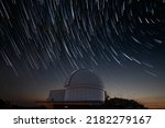 Astronomical observatory under star trails sky at night