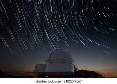 Astronomical observatory under star trails sky at night