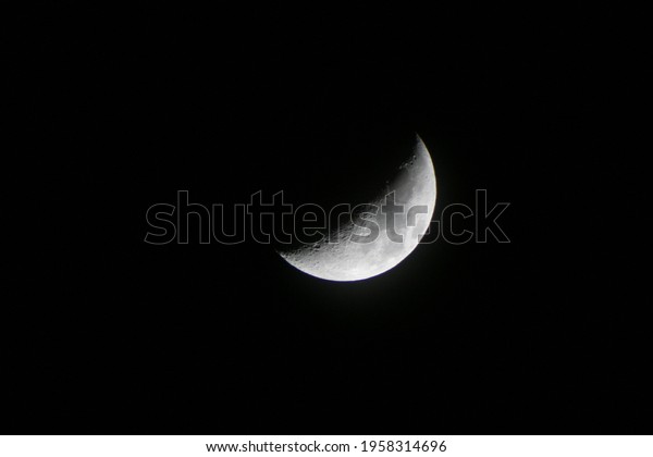Astronomical\
photography with telescope and attached camera, representing the\
moon in its intermediate phase called half moon, clearly visible\
both the craters and the lunar\
seas
