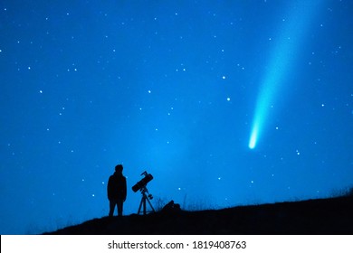 Astronomy Lover With A Telescope Observing A Comet In The Blue Starry Sky At Night. Silhouette Of A Person Observing The Immensity Of The Universe And The Stars. Trace Of A Comet Or A Shooting Star.