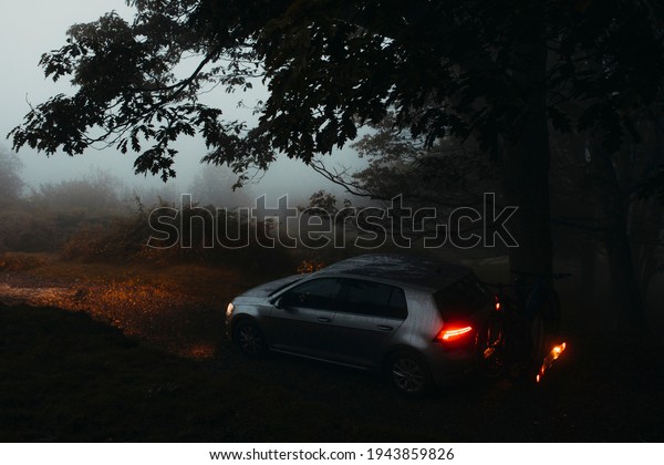 Asturias, Spain - September 9th 2020:  Volkswagen\
Golf VII, with mountain bikes in the back, being driven by a\
mountain path, with misty light, and entering into the forest, in\
Asturias forest,\
Spain.