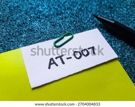 AT-007 writting on table background.