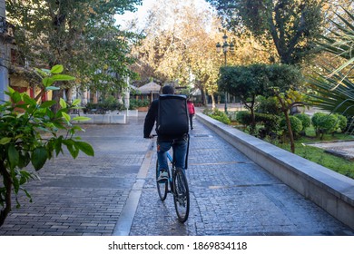 Athens City Center, Greece. December 5 2020. Biker With A Backpack On Empty Cobblestone Street, Winter Day. COVID 19 Pandemic Lockdown