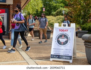 Athens, Georgia - August 27, 2021: Students walk past a portable sidewalk sign advertising a coffee hour sponsored by the Office of International Student Life at the University of Georgia.