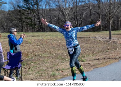 Athens, Georgia - January 1, 2020: A Female Runner Celebrates With Outstretched Arms During The New Years At Noon 5k Road Race.