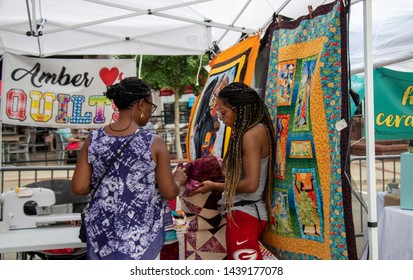 Athens, Georgia - June 22, 2019: A Quilt Vendor Shows A Handcrafted Quilt To A Customer In A Booth At The AthFest Music And Arts Festival.