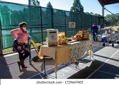 Athens, Georgia - May 9, 2020: During The COVID-19 Pandemic, A Vendor Wearing Protective Face Mask And Gloves Waits For Customers At The Athens Farmers Market.