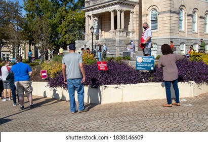 Athens, Georgia - October 16, 2020: A Poll Worker Answers Questions As Voters Wait In Line During Early Voting. Signs Remind Voters About Polling Place Restrictions And The Wearing Of Face Masks.