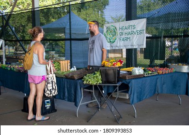 Athens, Georgia - September 5, 2020: During The COVID-19 Pandemic, A Customer Wearing A Face Mask Talks With A Vendor Wearing A Clear Face Shield At The Athens Farmers Market.