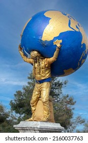 Athens , Greece - 27.03.2022: Street performer as the Titan Atlas holding the globe on his shoulders. sunny day with blue sky