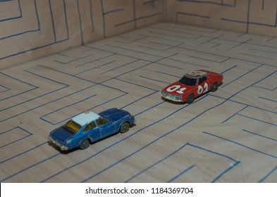 Athens, Greece – December 15, 2016: Old Matchbox Toy Cars Of The 70’s, Parked On A Wooden Deck With The Pattern Of A Labyrinth, Designed With A Blue Pen.