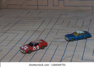 Athens, Greece – December 15, 2016: Old Matchbox Toy Cars Of The 70’s, Parked On A Wooden Deck With The Pattern Of A Labyrinth, Designed With A Blue Pen.