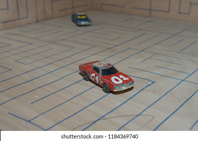 Athens, Greece – December 15, 2016: Old Matchbox Toy Cars Of The 70’s, Parked On A Wooden Deck With The Pattern Of A Labyrinth, Designed With A Blue Pen.