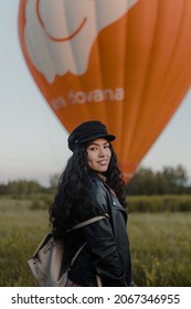 ATHENS, GREECE - Jun 07, 2021: A Vertical Shot Of An Attractive Hispanic Female Standing Near An Orange Hot Air Balloon