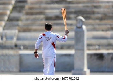 Athens, Greece - March 19, 2020: Olympic Flame handover ceremony for the Tokyo 2020 Summer Olympic Games. Greek Olympic medalist  E. Petrounias holds the Tokyo Olympic Flame at the Panathenaic stadium