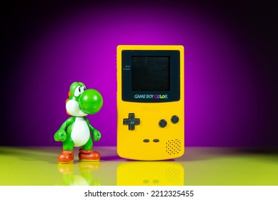 Athens Greece October 2 2022. Yellow Game Boy Color Handheld Game Console, With Yoshi Figure On A Purple Background With Reflection