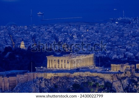 Athens monument at night - city top view with sea in background.