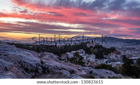 Athens & pink sunset. In the foreground is the ancient stones illuminated by the setting sun. View from the Acropolis to the west. Visible church, a museum, an observatory.