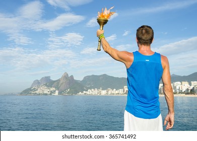 Athlete In Athletic Uniform Standing With Sport Torch In Front Of Rio De Janeiro Brazil Skyline At Ipanema Beach