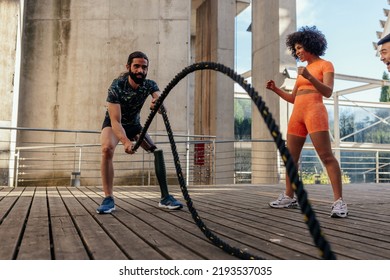 An athlete with a bionic leg is doing a strength exercise with ropes outdoors - Powered by Shutterstock