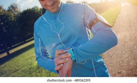 Athlete checking the program at his smart watch before running, lens flares