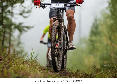 athlete cyclist on mountain bike riding uphill in forest front view. feet in drops mud. cross-country cycling competition - Powered by Shutterstock